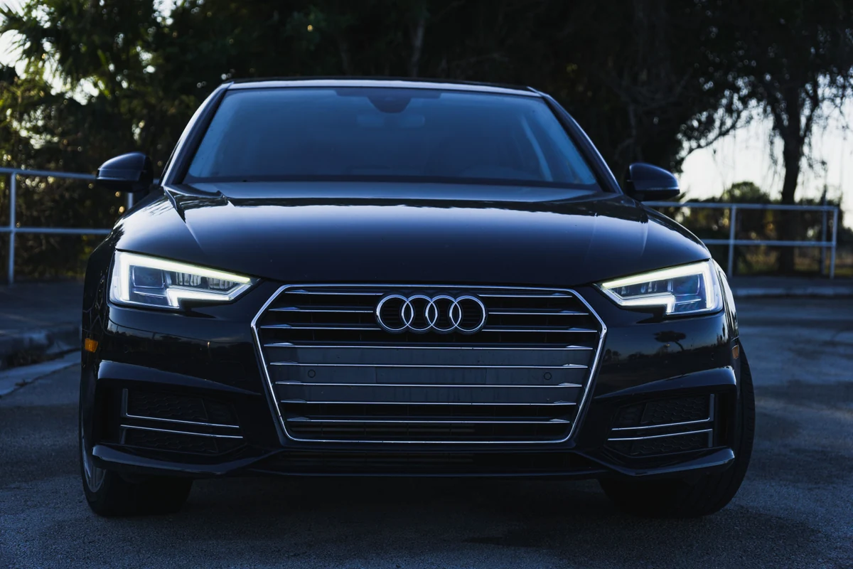 Gepflegter schwarzer Audi A4 in klarer Frontansicht vor einem ruhigen grünen Hintergrund